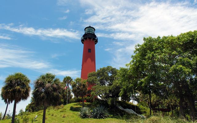 The red Jupiter Inlet Lighthouse rising above palms and mangroves in Jupiter